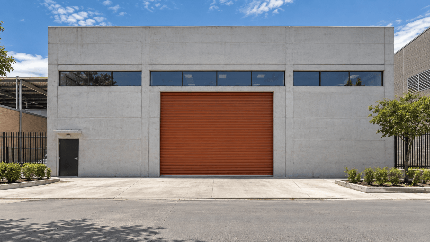 Fachada de bodega industrial con puerta de acceso naranja